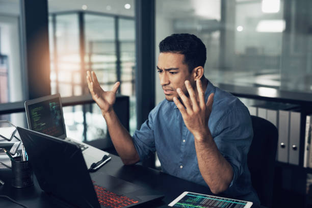 A man sits at his desk, visibly frustrated with his technology.