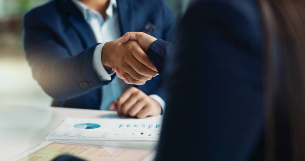 A man and woman shake hands over a M&A.