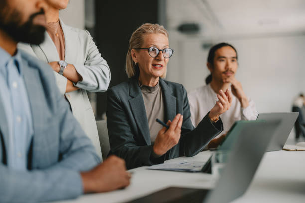 A businesswoman discusses various M&A risks with her partners in a meeting.