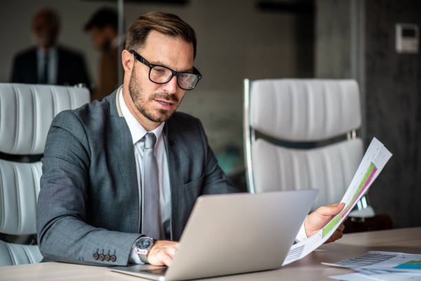 A businessman reviews charts and tables in front of his computer.