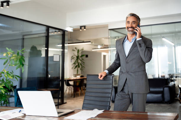 A man is on the phone at his desk, speaking with a potential client.